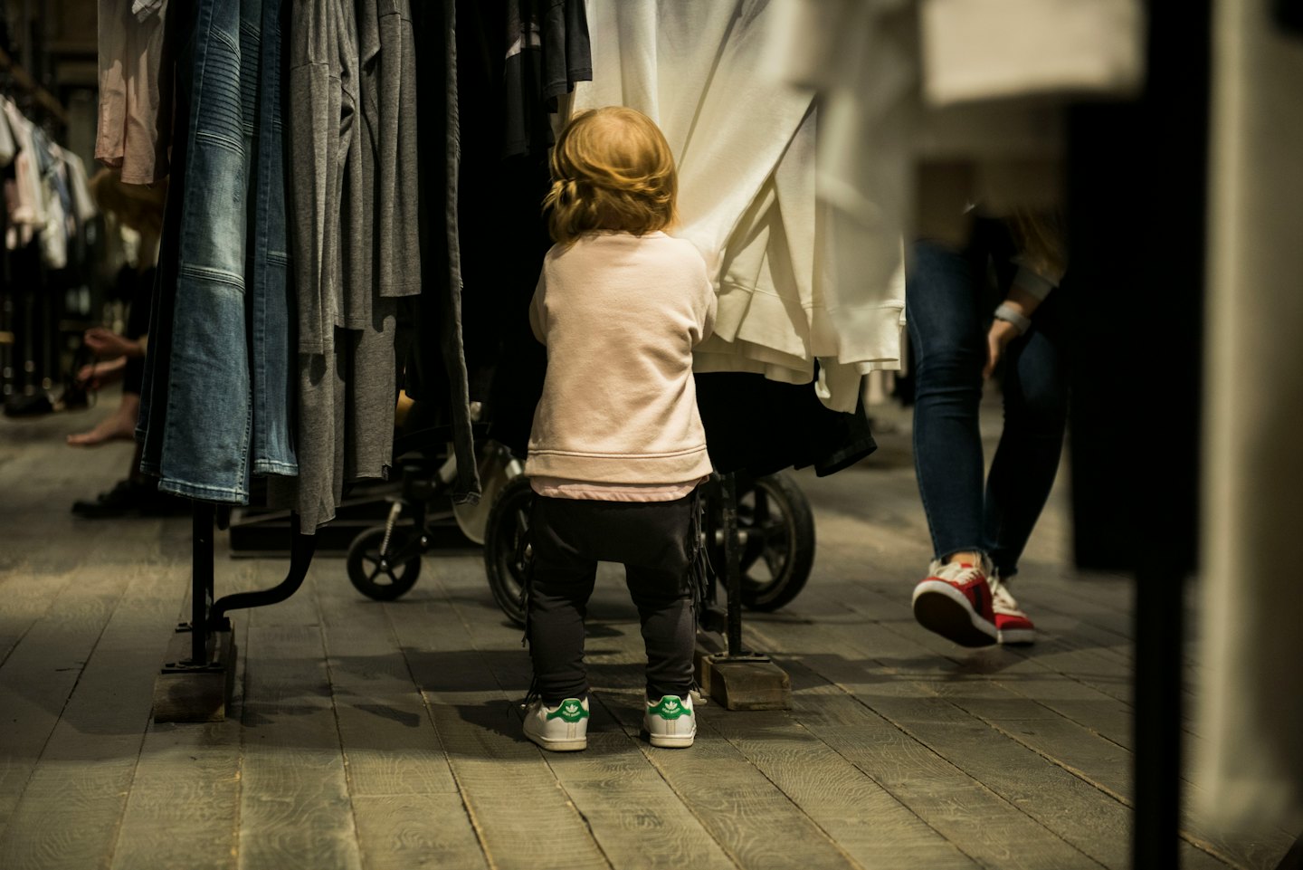Bambina in felpa rosa guarda gli scaffali dei vestiti in negozio.