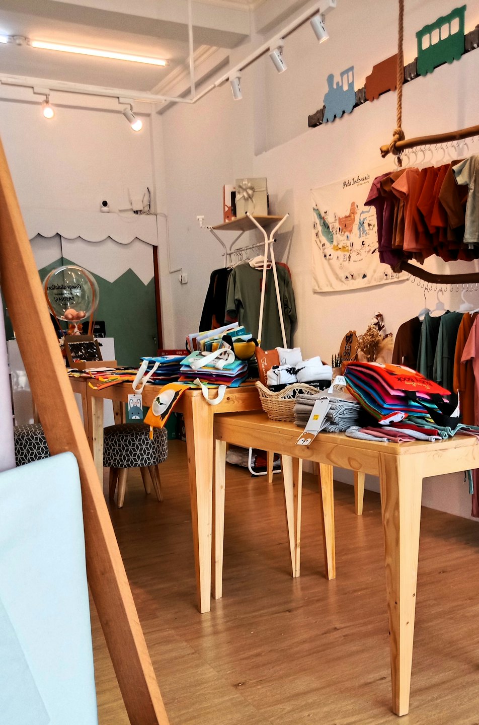 Boutique per bambini con tavoli in legno che espongono vestiti e accessori piegati.