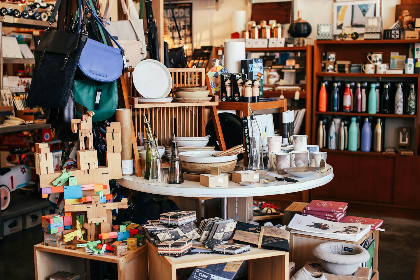 Scaffali e tavolo in legno che espongono articoli per la casa selezionati in una boutique.