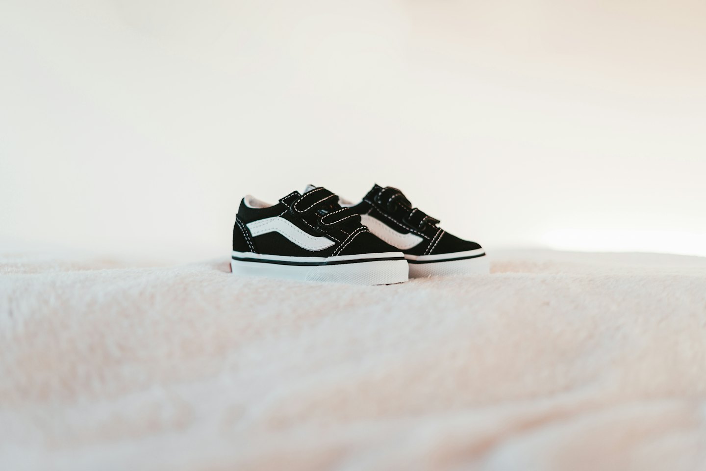 Scarpe da ginnastica per bambini con chiusura in velcro su una coperta rosa.